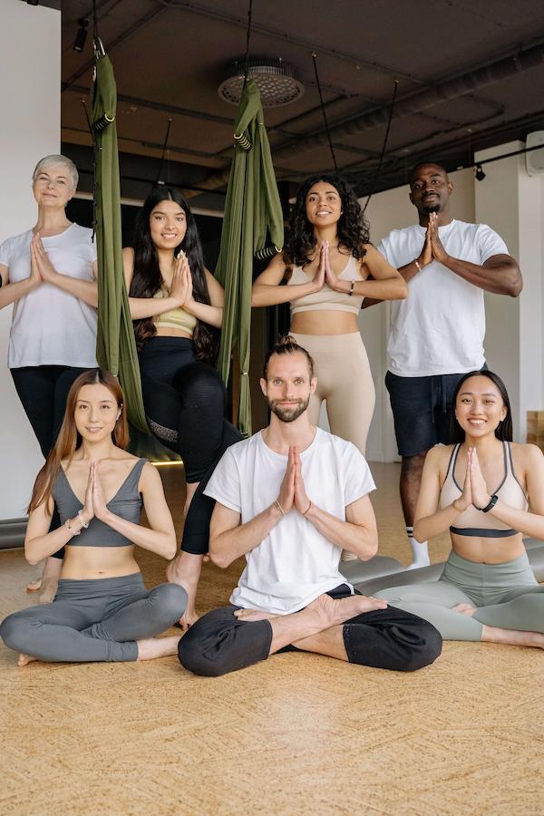 A multicultural group practicing yoga poses in an indoor studio setting.